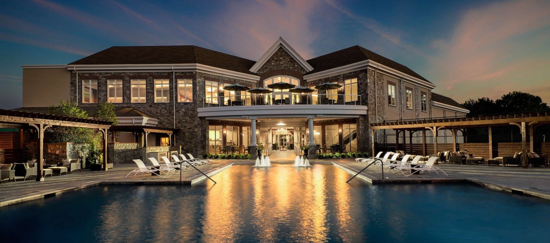 Building with pool that has fountains and lounging area