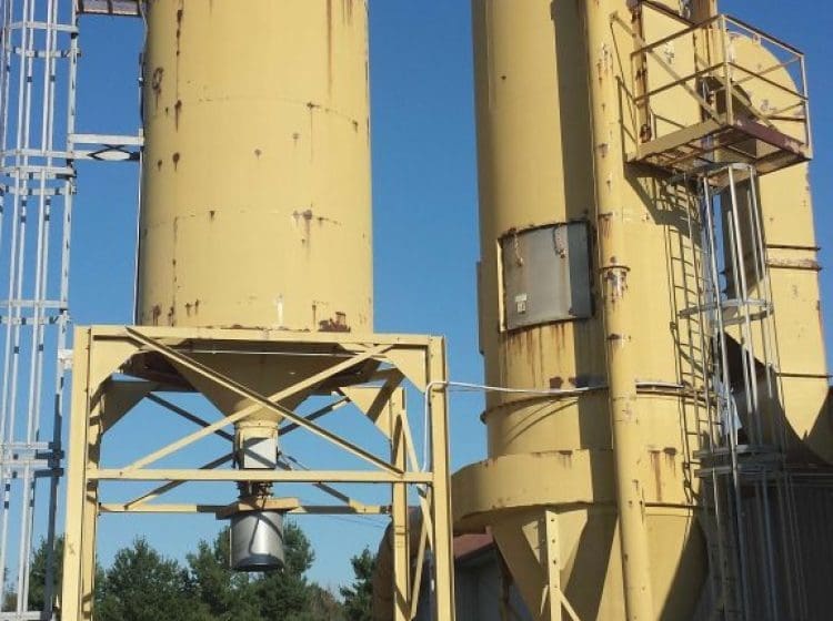 Yellow-painted industrial silos with visible wear, located near an outdoor work area.