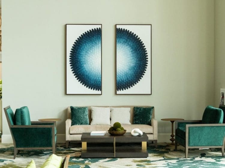 Seating area featuring a neutral sofa and two green armchairs. The wall is decorated with two large blue abstract art pieces, creating a bold focal point for the room.