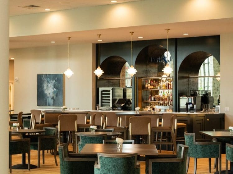 Modern bar and dining area featuring arched mirrors, pendant lights, and comfortable seating. The setting blends contemporary design with a warm, inviting atmosphere