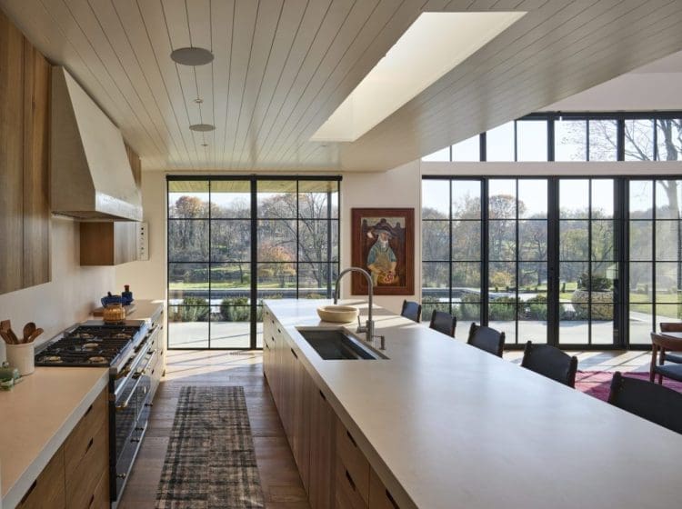 Open-concept kitchen with large windows and skylights, offering plenty of natural light. The kitchen features a long island with seating and a view of the backyard.