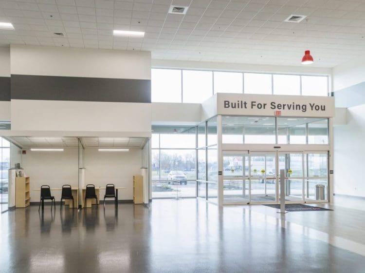 Modern commercial entrance with glass doors, large windows, and a sign reading 