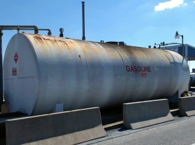 Industrial gasoline tank with protective coatings and visible hazard markings.