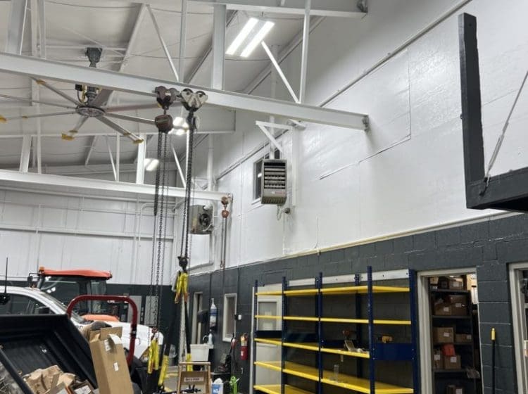 Industrial workshop with yellow and blue shelving, tractors, and a clean white and gray-painted interior.