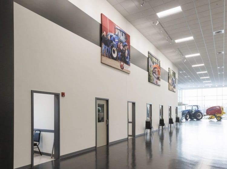 Interior showroom wall with doors and large hanging photos of agricultural machinery.