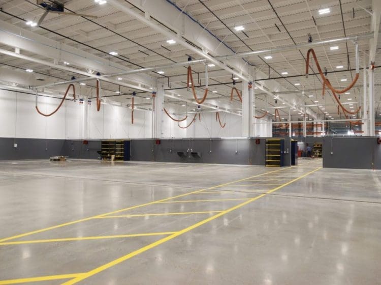 Large warehouse with polished floors, overhead ventilation, and yellow-lined pathways.