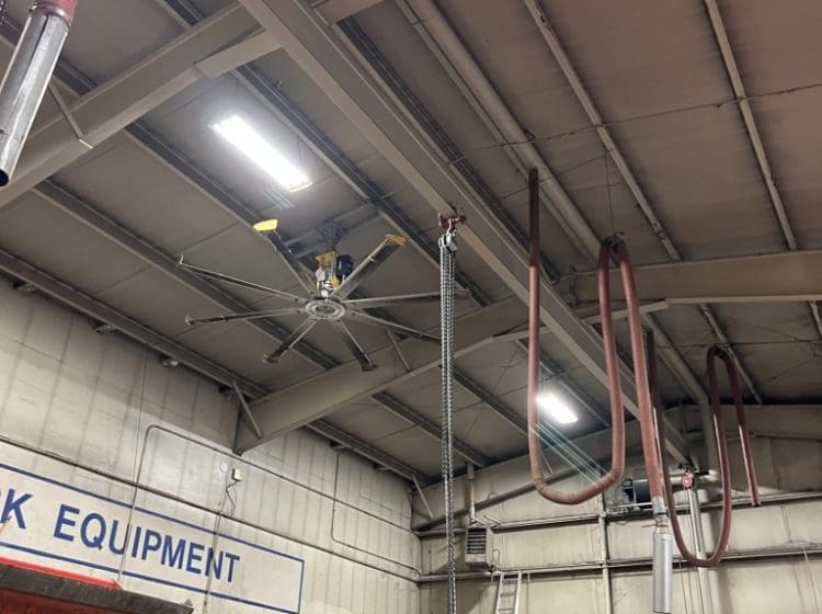 Ceiling of an industrial service center with exposed beams, ventilation pipes, and suspended equipment.