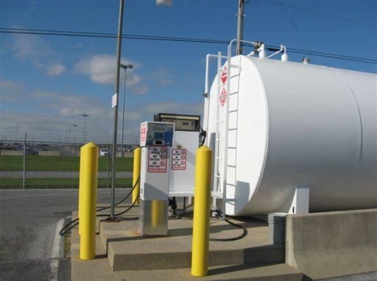 White powder-coated gasoline tank with attached fuel dispenser and bollards.