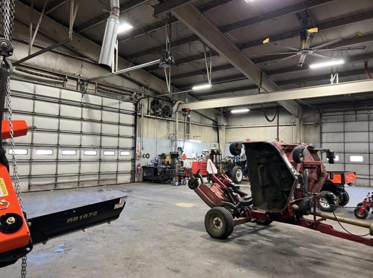 Spacious service facility with tractors and equipment near large garage doors and a clean concrete floor.