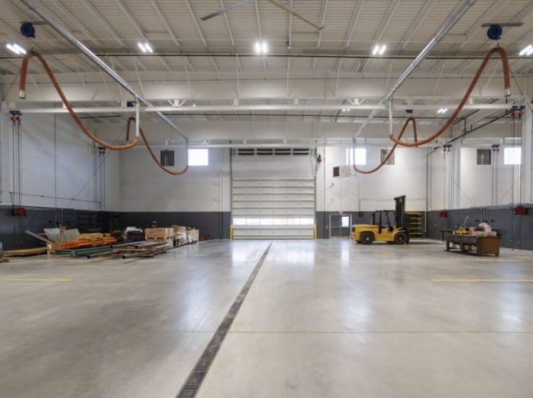 Spacious industrial garage with a forklift, materials on pallets, and a floor drainage system.