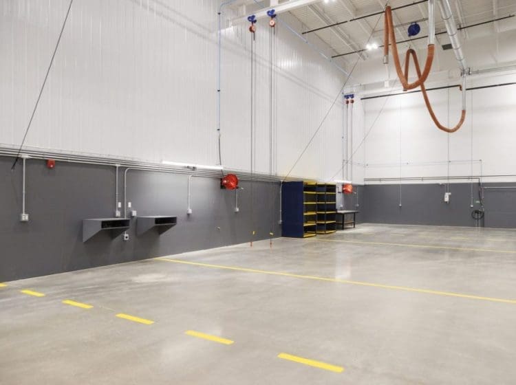 Clean industrial workspace with wall-mounted utility stations, yellow safety lines, and organized shelving.