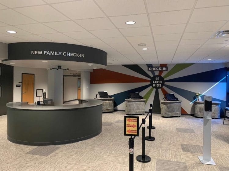 A colorful check-in area with a circular desk, bright wall graphics, and modern kiosks.