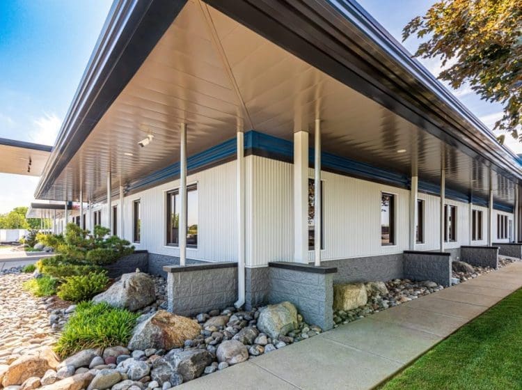 A sleek commercial building with a wraparound awning, landscaping, and modern architectural features.