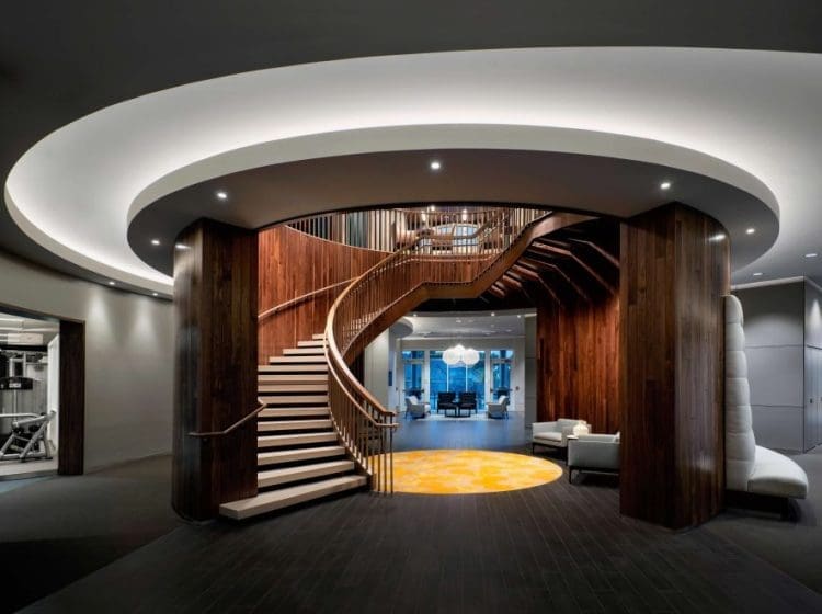 A luxury hotel lobby with a spiral wooden staircase, contemporary lighting, and stylish furnishings.