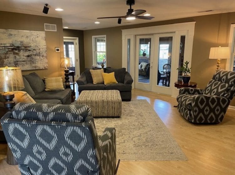 A cozy living room with neutral-colored walls, modern furniture, and large glass doors opening to a patio.
