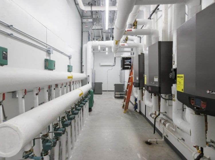 Industrial mechanical room featuring insulated pipes, boilers, and control panels in a clean layout.