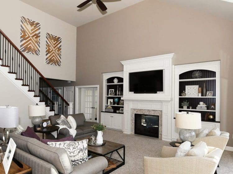 A spacious living room with vaulted ceilings, neutral walls, and comfortable seating centered around a fireplace.