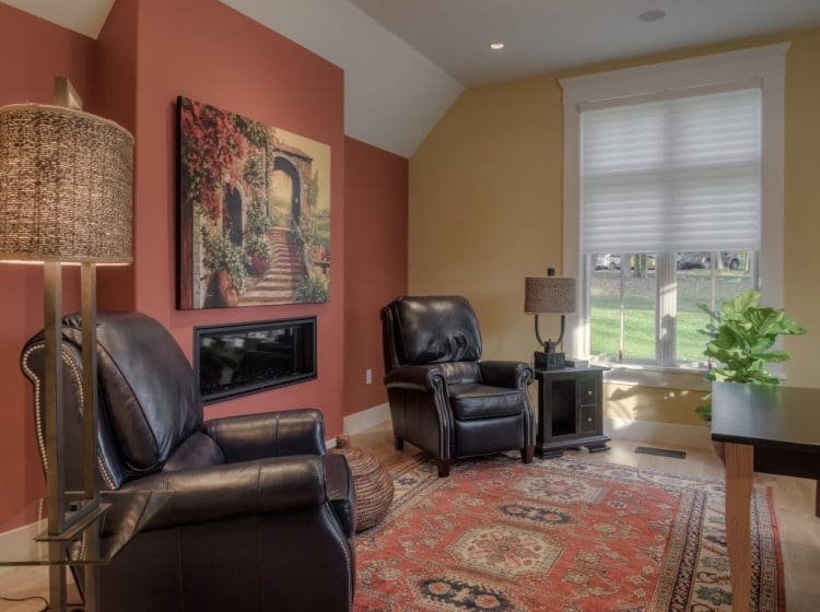 A cozy sitting area with leather chairs, colorful walls, and a large window letting in natural light.