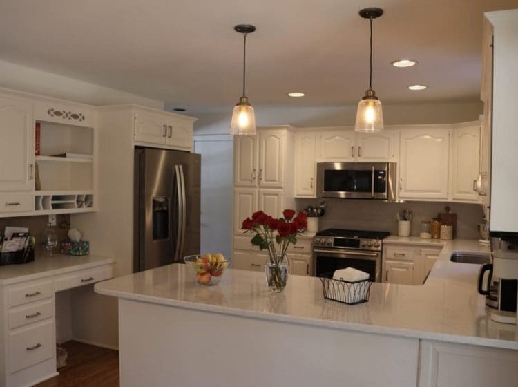 A sleek kitchen with white cabinetry, soft lighting, and stainless steel appliances.